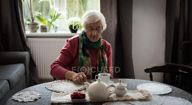 Старша жінка має чашку чаю у вітальні — стокове фото