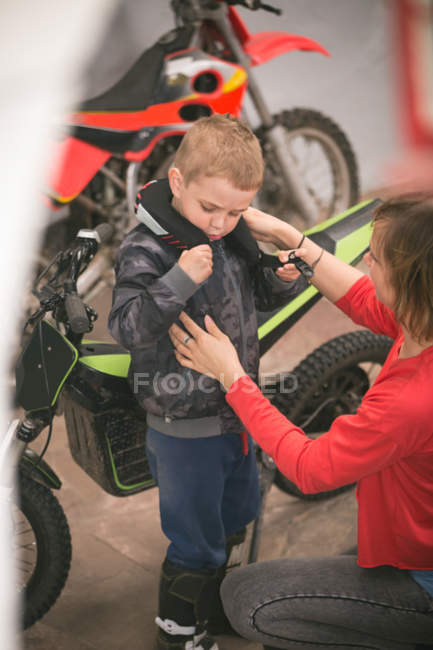 Mère préparant son fils pour faire du vélo dans le garage — Photo de stock
