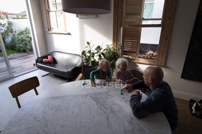 Pai e crianças brincando com barro na sala de estar em casa . — Fotografia de Stock