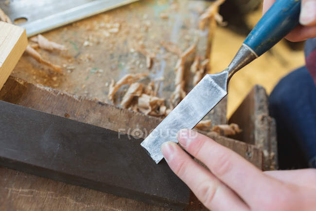 Gros plan du ciseau d'affûtage du charpentier mâle en atelier — Photo de stock