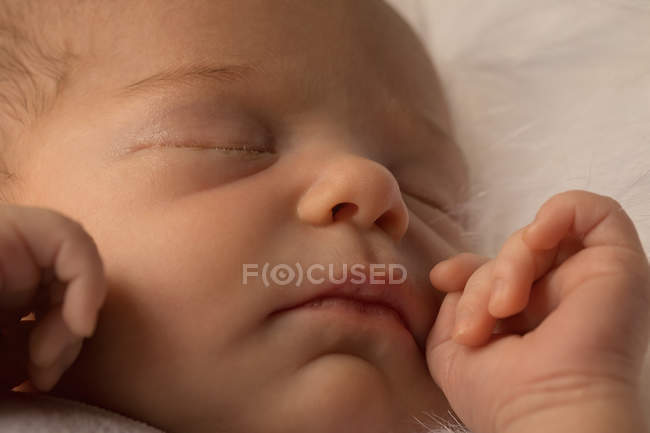 Primer plano de la cara del bebé recién nacido durmiendo en la cama del bebé
. - foto de stock
