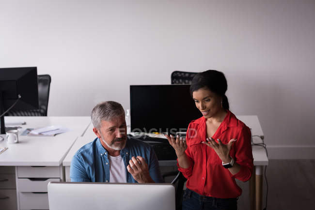 Коллеги по офису обсуждают на рабочем столе компьютер в креативном офисе — стоковое фото