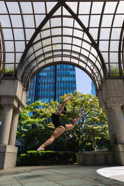 Female urban dancer dancing in street under arch. — Stock Photo