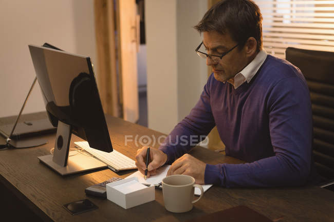 Businessman Working And Writing On Desk At Office Desktop Pc