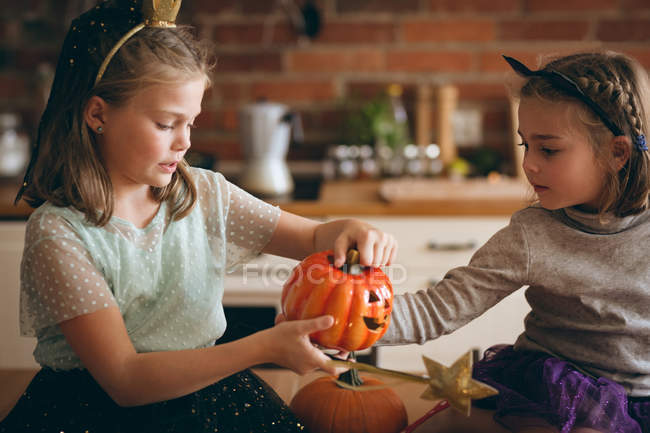 Sisters carving pumpkin in kitchen at home — Stock Photo