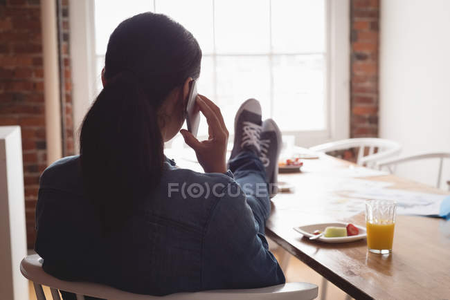 Женщина-руководитель разговаривает по мобильному телефону в креативном кабинете — стоковое фото