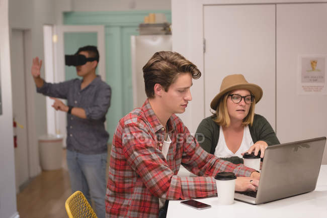 Executivos discutindo sobre laptop no escritório criativo — Fotografia de Stock