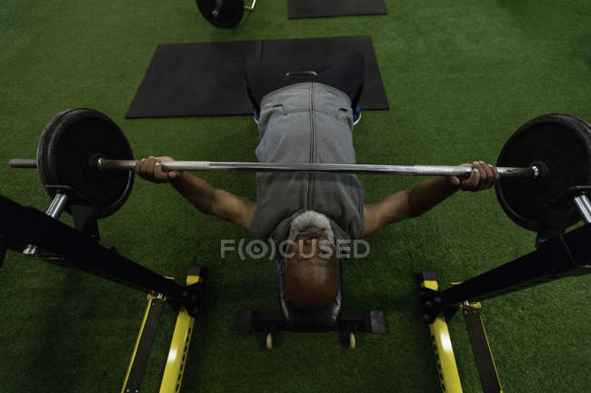 Vista de ángulo alto del hombre mayor haciendo ejercicio con barra de pesas en el gimnasio . - foto de stock