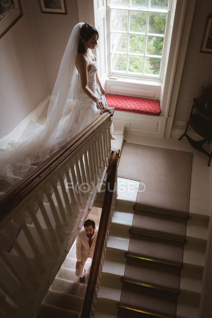 Mariée et marié marchant sur l'escalier à la maison — Photo de stock