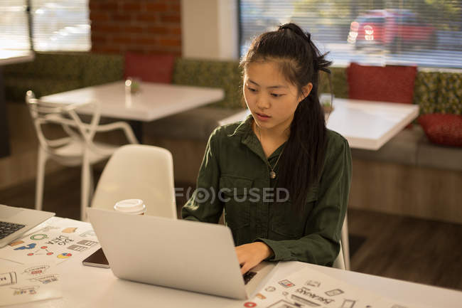 Жіночий керівник використовує ноутбук в кафетерії в офісі — стокове фото