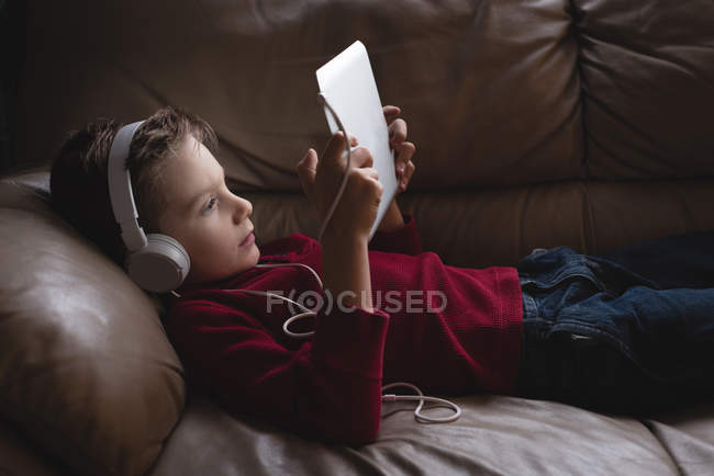 Junge nutzt digitales Tablet mit Kopfhörer im heimischen Wohnzimmer — Stockfoto