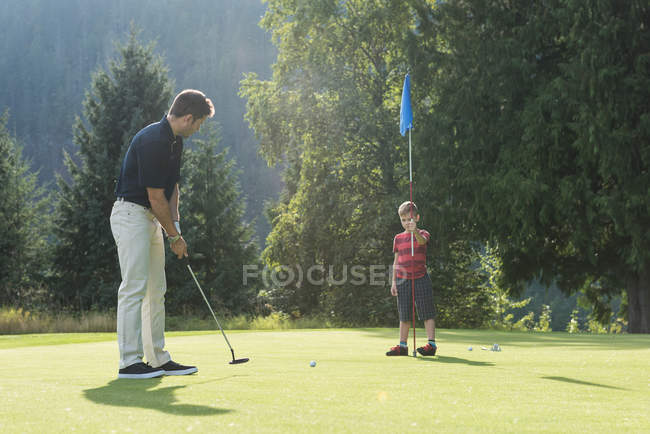 Padre e hijo jugando golf en el campo - foto de stock