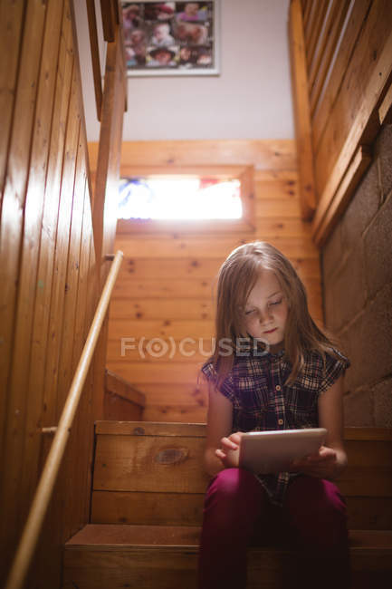 Linda chica usando tableta en la escalera en casa - foto de stock