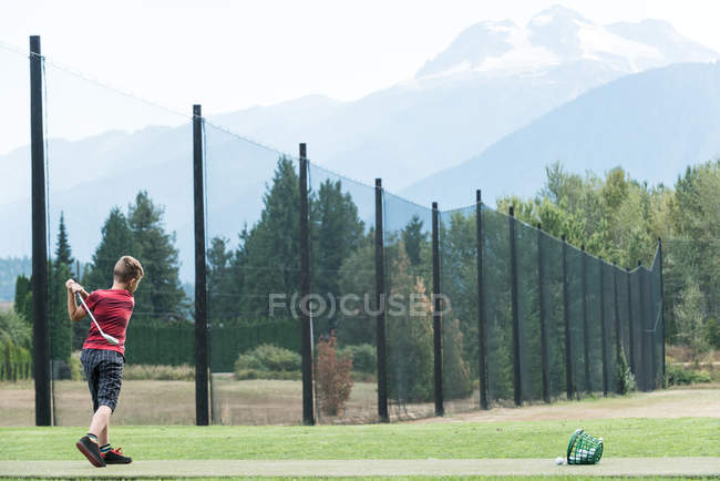 Rapaz atingindo tiro de golfe no campo de golfe — Fotografia de Stock