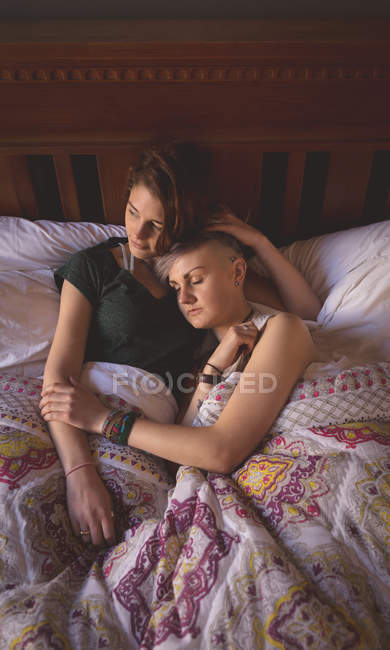 Lesbian couple cuddling on bed in bedroom at home. — Stock Photo