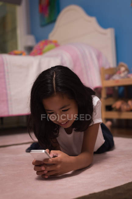 Girl using mobile phone in bedroom at home — Stock Photo