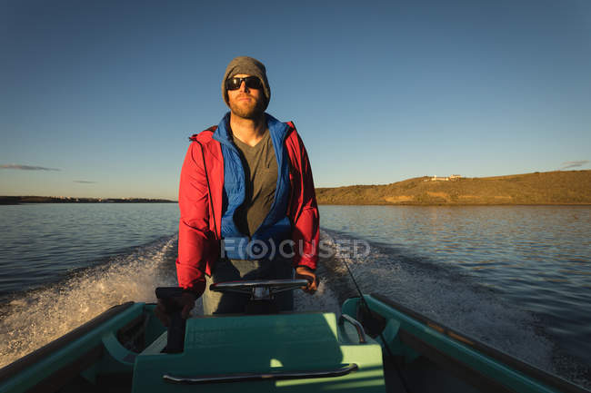Mann fährt mit Motorboot in Fluss im Sonnenlicht. — Stockfoto