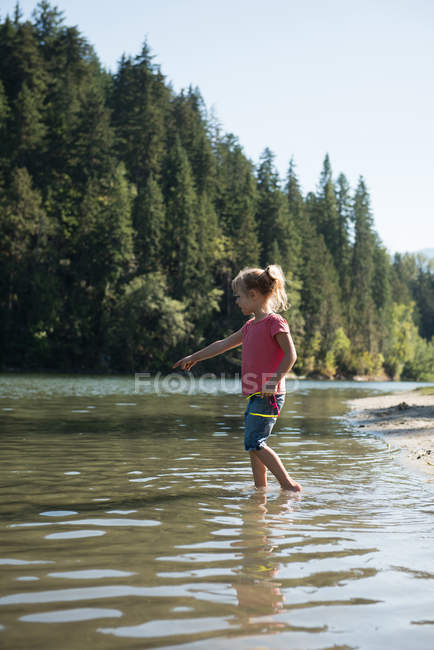 Fille jouer dans la rivière par une journée ensoleillée — Photo de stock