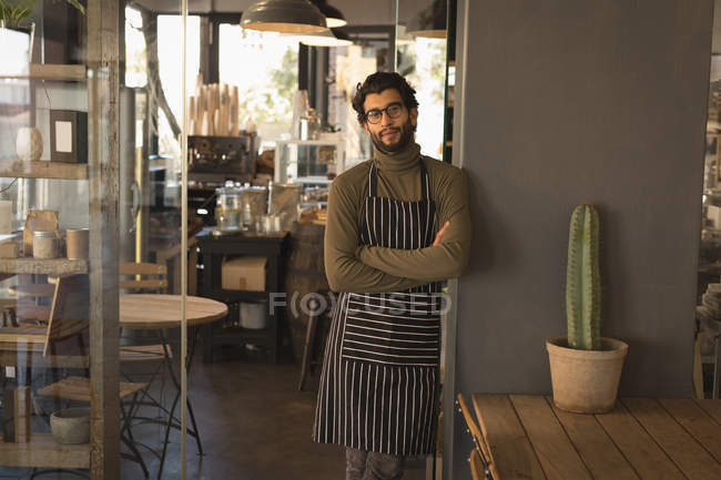 Portrait of waiter standing with arms crossed in coffee shop — Stock Photo