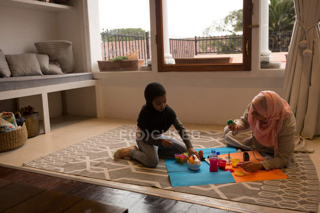 Muslim girl and her mother doing watercolor painting at home — Stock Photo