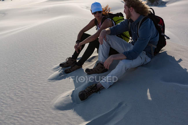 Couple relaxant sur le sable dans le désert par une journée ensoleillée — Photo de stock