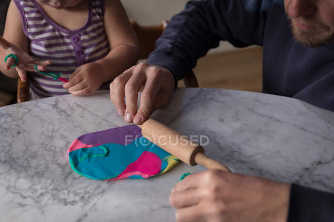 Pai enrolando argila com a filha em casa . — Fotografia de Stock