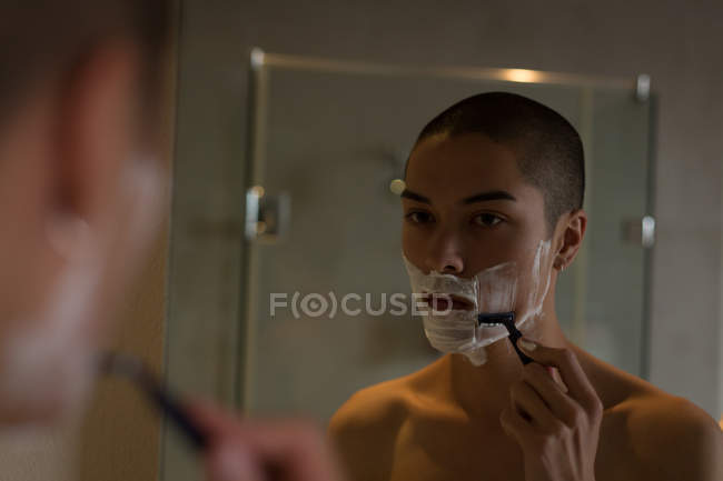 Jeune homme rasant sa barbe dans la salle de bain — Photo de stock