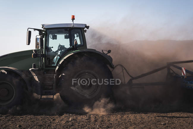 Trator arar o campo em um dia ensolarado — Fotografia de Stock
