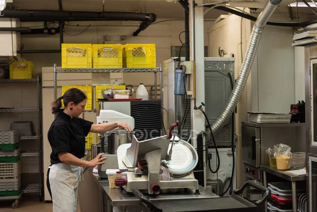 Концентрований шеф-кухар використовує шліфувальну машину на комерційній кухні — стокове фото