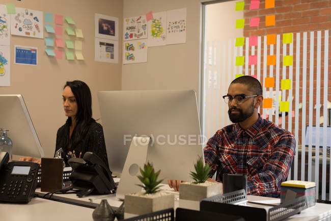 Compañeros de negocios trabajando en la computadora en el escritorio en la oficina - foto de stock