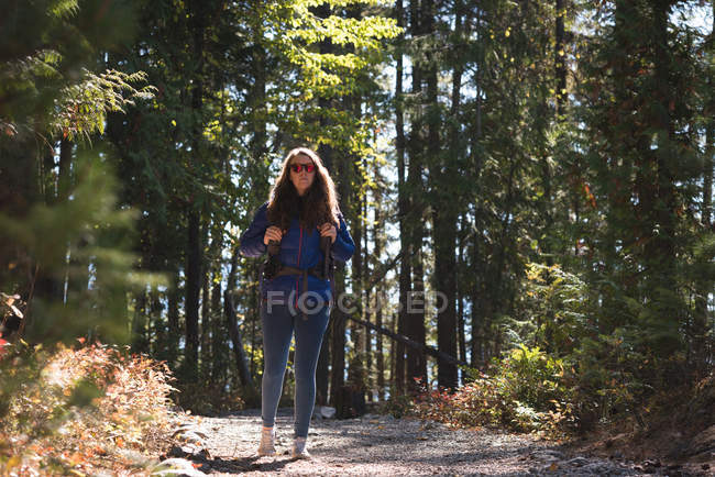 Female hiker standing with backpack in forest on a sunny day — Stock Photo