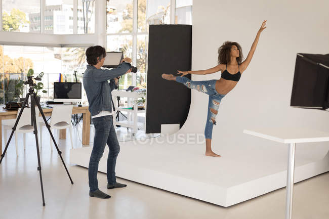 Fotógrafo profissional tirando foto de modelo em estúdio — Fotografia de Stock