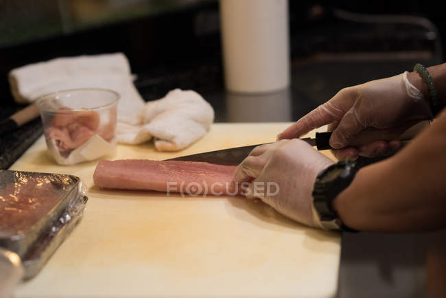 Chef filetant du poisson dans la cuisine du restaurant sur une planche à découper — Photo de stock