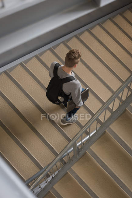 Vue grand angle de l'étudiant marchant avec ordinateur portable sur escalier — Photo de stock