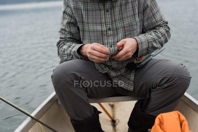 Sección media del hombre sosteniendo alicates en su mano en el barco - foto de stock