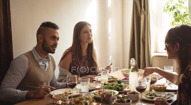 Друзі, взаємодіючих маючи їжу за столом — стокове фото