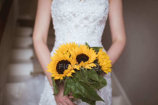 Mid section of bride holding a flower bouquet — Stock Photo
