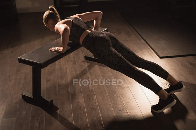 Woman doing push-ups on bench in gym — Stock Photo