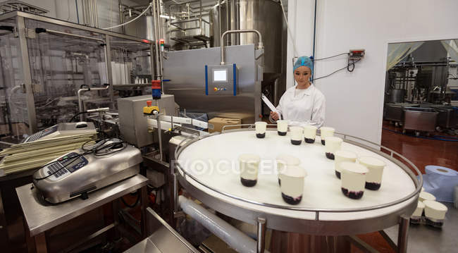 Female worker monitoring the food jars on the production line in the factory — Stock Photo