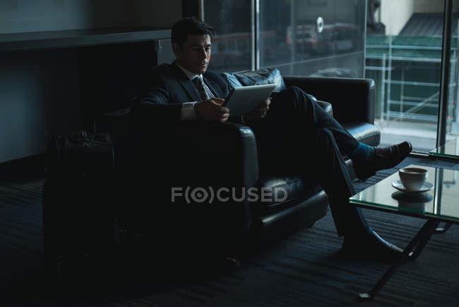Businessman using digital tablet in office lobby — Stock Photo