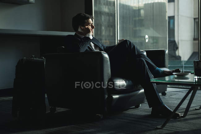 Businessman talking on phone while having coffee in hotel — Stock Photo