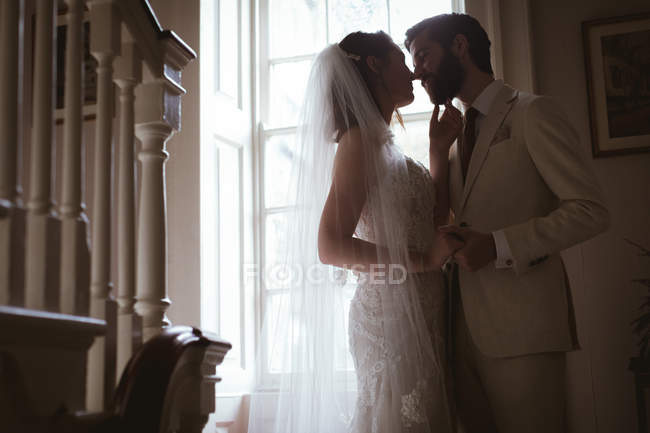 Noiva e noivo beijando na escada em casa — Fotografia de Stock