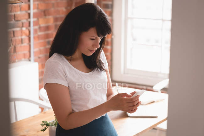 Femme exécutive utilisant le téléphone portable dans le bureau de création — Photo de stock