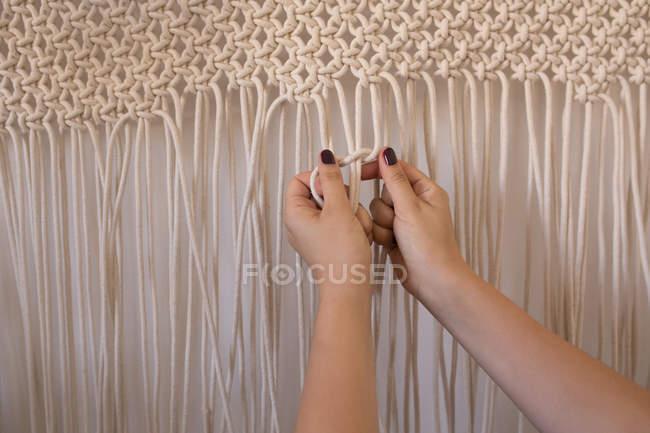 Woman knotting strings against wall — Stock Photo