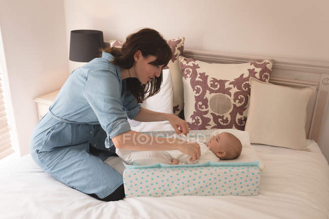 Милий маленька дитина одягався мама на ліжку в спальні в домашніх умовах — стокове фото