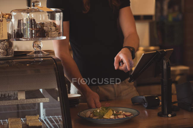 Средняя секция официанта принимает заказ на цифровой планшет в кафе — стоковое фото