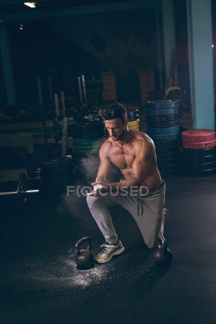М'язистий чоловік натирає порошок в руках у фітнес-студії — стокове фото