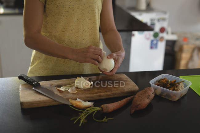 Mid section of woman peeling sweet lime in kitchen — Stock Photo