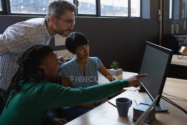 Business executives discussing over computer at desk in office. — Stock Photo