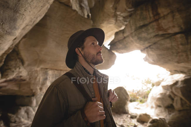 Escursionista che ispeziona rocce in una grotta in una giornata di sole — Foto stock
